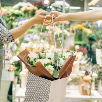 Flower shop business concept, florist in apron and female customer in floral boutique.